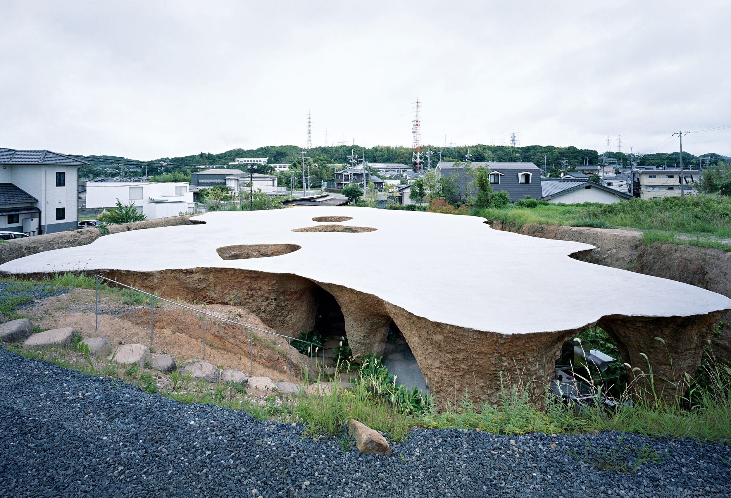 從地面俯瞰這棟建築。由於基地地勢較高，從周圍無法窺見內部情況。屋頂朝向作為中庭的中央開口處呈傾斜狀，設計上使雨水流向三個庭院中的其中一個。